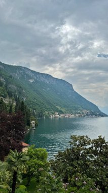 Como Gölü, İtalya. Dağlar ve göl manzarası yemyeşil, sakin sular, bulutlu gökyüzü altında yemyeşil ve sakin sular, doğa konsepti, güzel bir manzara