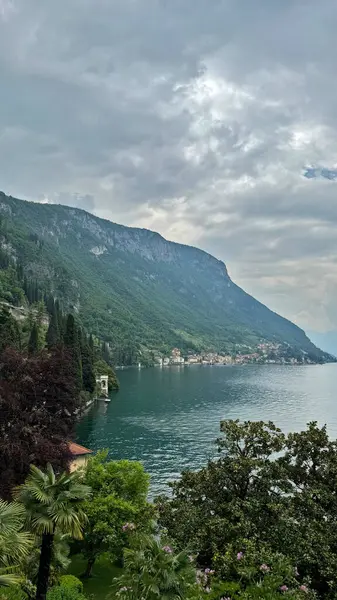 Como Gölü, İtalya. Dağlar ve göl manzarası yemyeşil, sakin sular, bulutlu gökyüzü altında yemyeşil ve sakin sular, doğa konsepti, güzel bir manzara