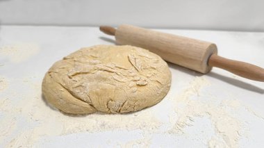 Taze hazırlanmış hamurlar mutfak tezgahında, merdane eşliğinde, evde pişirme ve yemek pişirme sevincini vurguluyor, aşçılar ve aşçılar için mükemmel.