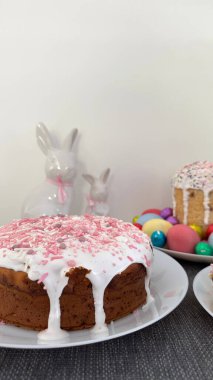 Pembe kremalı ve şekerli pasta, canlı paskalya yumurtaları ve büyüleyici tavşanlarla birlikte bir tabakta duruyor. Kutlamalar ve toplantılar için ideal bir ortam yaratıyor.