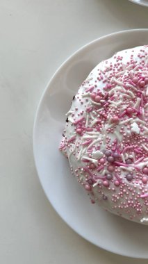 Yuvarlak pasta pembe süslemeler ve beyaz bir tabakta krema ile süslenmiş. Kutlamalar ve özel durumlar için ideal tatlı sunuluyor. Sevinç veren tatlı bir ikram.