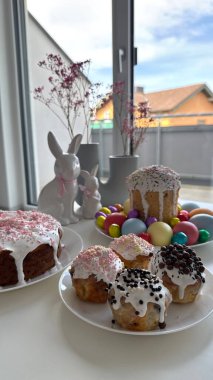 Paskalya için pişirilen eşyalar ve boyalı yumurtalar canlı dekorasyonlar ve çiçeklerle dolu bir masada düzenlenerek, kutlamalar ve toplantılar için neşeli bir ortam yaratılıyor, bahar şenlikleri ve özel kutlamalar için ideal hale getiriliyor.
