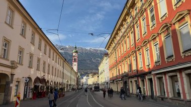 Innsbruck, Avusturya - 28 Mart 2025: Innsbruck şehir manzarası tarihi binalar, karla kaplı dağlar ve kentsel kültür ve yaşamı ön plana çıkaran canlı sokaklar