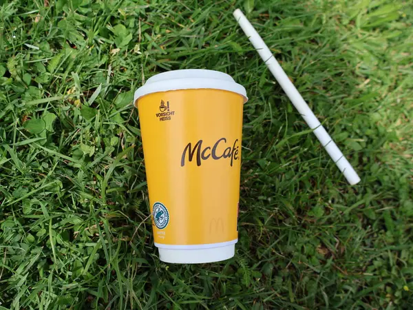 29.05.2025 Almanya: McDonalds 'ın kağıt bardağı ve samanı çimlerin üzerine atılmış, fast food ambalajlarının çevresel kirliliğini gösteriyor. Bir McCafe marka kahve fincanı ve çimlerin üzerine atılmış bir kağıt kamış.