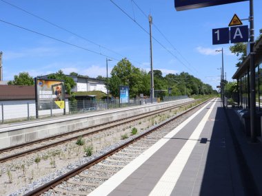 31.05.2025 Kolbemoor, Almanya: Berrak Mavi Gökyüzü ile güneşli bir günde Almanya 'da Sessiz Demiryolu Platformu. Güneşli bir günde çekilen terk edilmiş bir tren platformu temiz hatlar, raylar ve