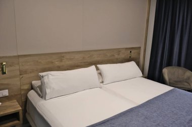 Modern otel odasının içinde rahat çift kişilik yatak ve tahta yatak başlığı var. Hoş bir otel odası, düzgün düzenlenmiş çift kişilik bir yatak, minimalist ahşap mobilyalar ve yumuşak ışıklandırma. Tam oldu.