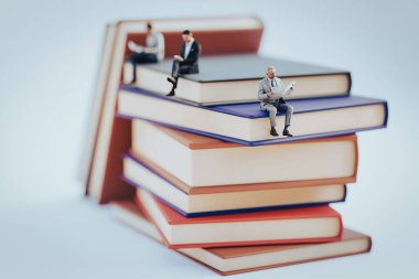 Minyatür insanlar arka plan eğitimi ya da iş konsepti olarak kitap üzerinde oturuyorlar. 3B illüstrasyon