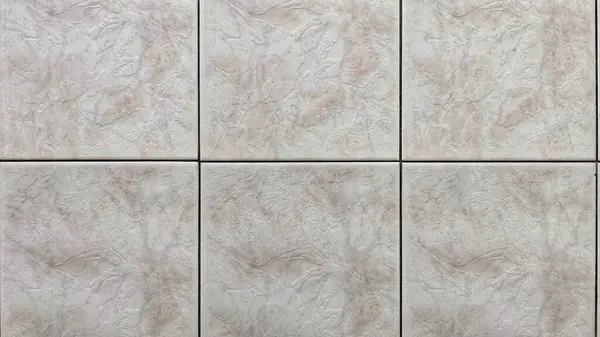 Seramik duvar fayanslarının yakın plan görüntüsü, ince girdaplar ve açık gri ve soluk pembemsi tonlarda doğal taş dokularını gösteren ızgara desenli düzende düzenlenmiş.