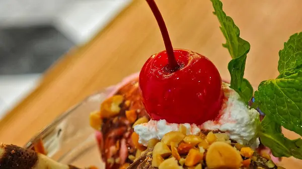 Canlı bir kırmızı kirazın seçici odak noktası dondurmanın tepesidir. Makro yüzeysel alan derinliği ile kapat.