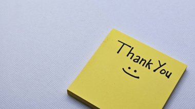 Gri arka planda izole edilmiş sarı yapışkan nottaki gülümseme ikonu ile teşekkür ederiz..