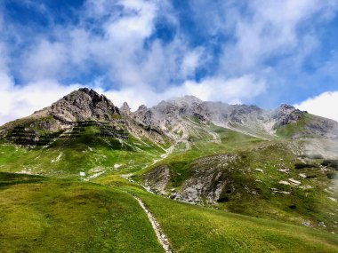 Avusturya Alplerinde, kayalık tepeleri, yeşil çayırları ve mavi bulutlu gökyüzü olan muhteşem bir dağ manzarası. Aziz Anton am Arlberg