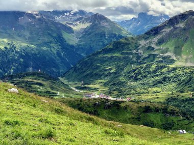 Avusturya Alplerinde, kayalık tepeleri, yeşil çayırları ve mavi bulutlu gökyüzü olan muhteşem bir dağ manzarası. Aziz Anton am Arlberg