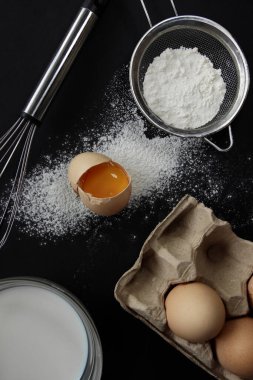 Kahvaltı hazırlamak için gerekli malzemeler. Arka planda kırık bir yumurta.