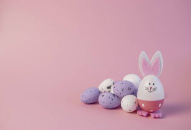 Paskalya tavşanı ve pembe arka planda yumurtalar. Paskalya tebrik kartı.