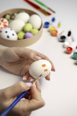 Fırça ve paskalya yumurtalarıyla yumurta boyayan kadın, yakın plan.