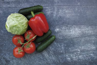 Ahşap bir arka planda taze sebzeler. Domates, salatalık, lahana, dolmalık biber ve salatalık. Sağlıklı gıda, taze malzeme ve vejetaryen mutfağı kavramı.