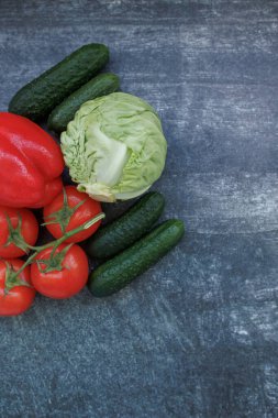 Gri arka planda taze çiğ sebzeler. Domates, salatalık, lahana, dolmalık biber ve salatalık. Sağlıklı gıda, taze malzeme ve vejetaryen mutfağı kavramı.