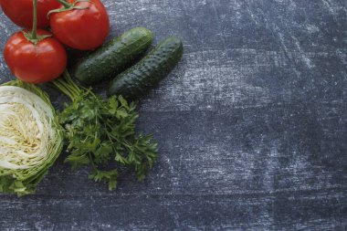 Ahşap arka planda taze salatalık, sarımsak, ot ve sebze karışımı, üst manzara. Metin için boşluk