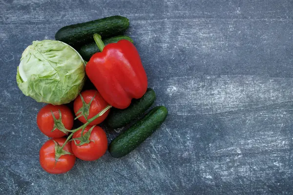 Ahşap bir arka planda taze sebzeler. Domates, salatalık, lahana, dolmalık biber ve salatalık. Sağlıklı gıda, taze malzeme ve vejetaryen mutfağı kavramı.
