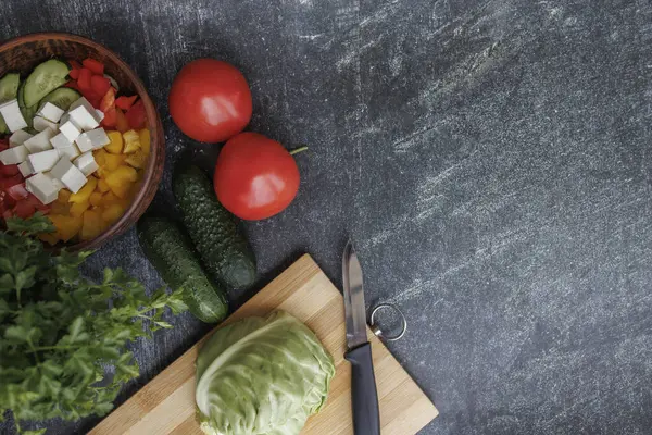 Siyah arka planda taze sebze ve baharatlar, sağlıklı beslenme. Siyah arka planda taze sebzeler ve baharatlar, sağlıklı yiyecekler. Bir tabakta doğranmış sebzeler, doğranmış lahana ile birlikte kesme tahtasının yanında.