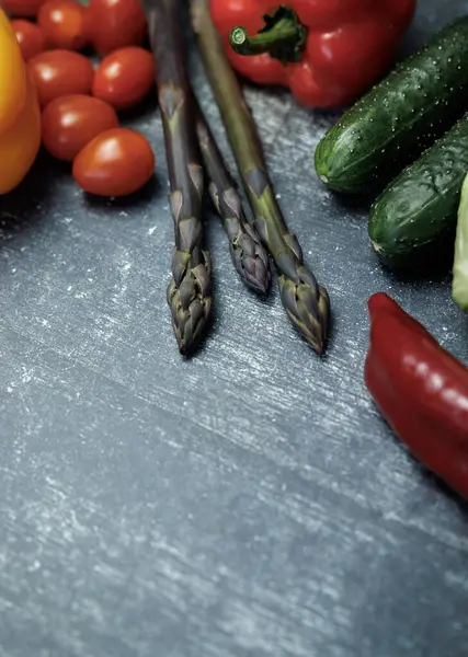 Siyah arka planda taze sebzeler ve meyveler. Sağlıklı beslenme. Karanlık bir yüzeyde taze sebze ve otlar. kuşkonmaz, kiraz domatesleri, dolmalık biber, salatalık, lahana. 