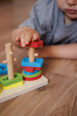 Ahşap eğitici şekil ayırıcı oyuncakla oynayan bir çocuğun yakın çekimi. Ellere ve renkli geometrik şekillere odaklan. Oyun, iyi motor beceriler ve erken çocukluk gelişimi yoluyla öğrenme kavramı