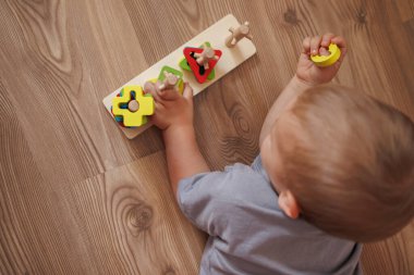 Küçük çocuk evde eğitici tahta oyuncaklarla oynuyor. Üst Manzara. Erken çocuk gelişimi kavramı, oyun ve iyi motor becerilerle öğrenme. Metin için boşluk