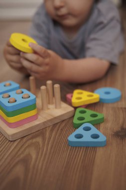 Ahşap eğitici oyuncak ayırıcıyla oynayan çocuk ellerine yakın plan. Yatay fotoğraf. Oyun yoluyla öğrenme kavramı, iyi motor beceriler ve erken çocukluk gelişimi