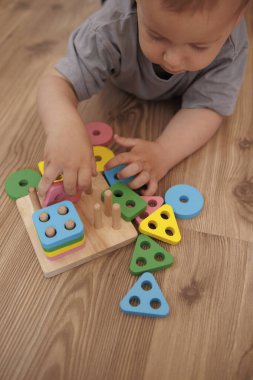Küçük bebek geometrik figürlerle oynuyor. Renkleri öğrenmek. Erken öğrenme kavramı oyun, iyi motor beceriler ve erken çocukluk gelişimi yoluyla.