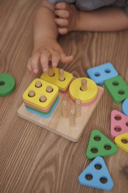 Ahşap eğitici oyuncak ayırıcıyla oynayan çocuk ellerine yakın plan. Yatay fotoğraf. Oyun yoluyla öğrenme kavramı, iyi motor beceriler ve erken çocukluk gelişimi