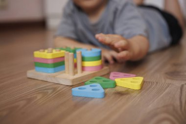 Ahşap eğitici oyuncak ayırıcıyla oynayan çocuk ellerine yakın plan. Yatay fotoğraf. Oyun yoluyla öğrenme kavramı, iyi motor beceriler ve erken çocukluk gelişimi