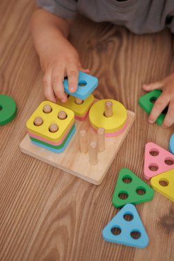 Ahşap eğitici oyuncak ayırıcıyla oynayan çocuk ellerine yakın plan. Yatay fotoğraf. Oyun yoluyla öğrenme kavramı, iyi motor beceriler ve erken çocukluk gelişimi