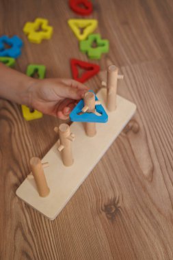 Childs 'ın elleri ahşap Montessori ayıklama oyuncağına şekil veriyor. Bebekler için renkli eğitim oyuncağı, iyi motor becerileri, koordinasyonu ve bilişsel gelişimi teşvik ediyor.