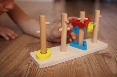 Ahşap eğitici şekil ayırıcı oyuncakla oynayan bir çocuğun yakın çekimi. Ellere ve renkli geometrik şekillere odaklan. Oynayarak öğrenme kavramı, ince motor beceriler, 