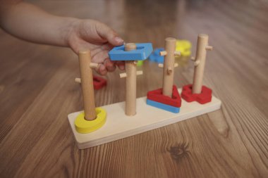 Childs 'ın elleri ahşap Montessori ayıklama oyuncağına şekil veriyor. Bebekler için renkli eğitim oyuncağı, iyi motor becerileri, koordinasyonu ve bilişsel gelişimi teşvik ediyor.