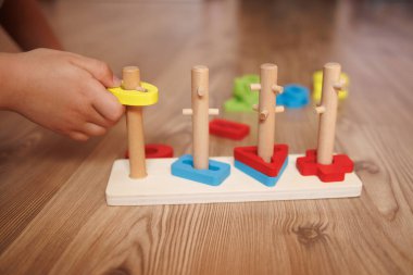 Childs 'ın elleri ahşap Montessori ayıklama oyuncağına şekil veriyor. Bebekler için renkli eğitim oyuncağı, iyi motor becerileri, koordinasyonu ve bilişsel gelişimi teşvik ediyor.