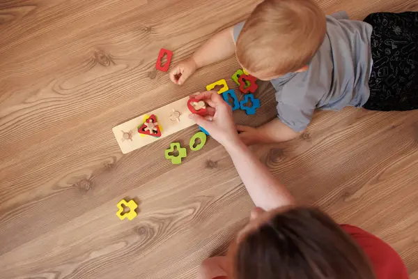 Küçük bebek, annesiyle zemin üstünde oynuyor. Erken öğrenme kavramı oyun, iyi motor beceriler ve erken çocukluk gelişimi. Anne ve bebek. Mesaj için yer var.