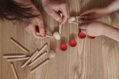 Çocuk renkli ahşap çubuklardan bir piramit yapıyor..