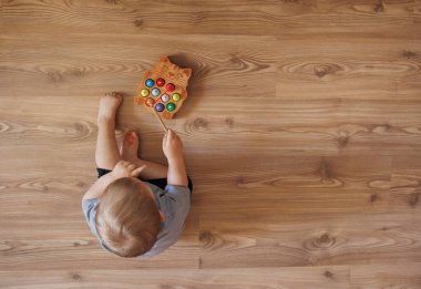 Küçük çocuk yerde oturuyor ve kameraya bakıyor.