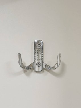 Beyaz bir arka plandaki metal vidanın yakın plan çekimi. Arka planda izole edilmiş havlu askısı.