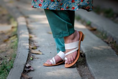 A woman wearing floral design Indian chappals clipart