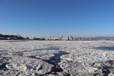 A panorama of a riverside of Quebec city in winter with icebergs. The St-Laurent river in winter. The nature in December in Quebec and Canada. A coast with factories and environment. clipart