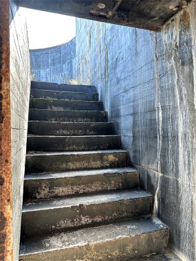 Yıpranmış beton bir merdiven, Fort Pickens, Florida 'daki eski duvarlar tarafından çerçevelenmiş parlak güneş ışığına doğru yükseliyor. Sahne sessiz bir esneklik, gizem ve tarihte bir yolculuğu çağrıştırıyor..