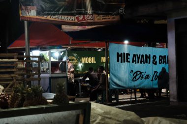 Pacitan, Indonesia - September 26, 2024: A stall selling chicken noodles (mie ayam) and meatballs (bakso) at night. clipart