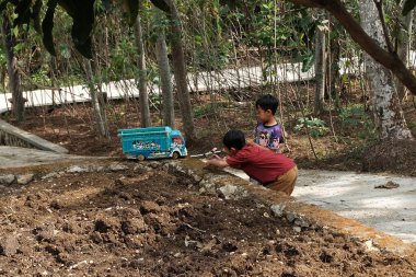 Pacitan, Endonezya - 25 Eylül 2024: Mavi oyuncak kamyonla oynayan çocuklar.