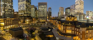 Tokyo İstasyonu binasının gece görüşü ve Marunouchi, Chiyoda-ku, Tokyo, Japonya 'daki KITTE Garden' dan görülen kırmızı tuğlalardan yapılmış yüksek binalar.