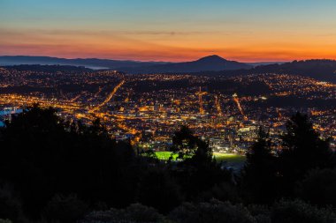 Günbatımı gökyüzü ve Dunedin 'in gece manzarası Yeni Zelanda, Dunedin' deki Sinyal Tepesi Gözcüleri 'nden görüldüğü gibi.