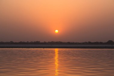 Gökyüzü Ganj Nehri 'nin erken saatlerinde turuncuya boyandı ve Hindistan' ın Varanasi şehrinde sabah güneşi...
