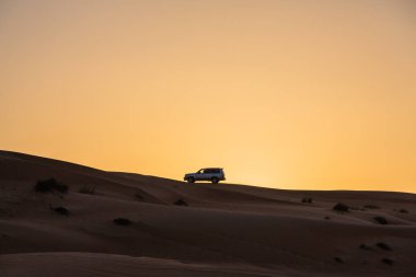 Umman Çölü 'nde ve günbatımı gökyüzünde giden arabalar.