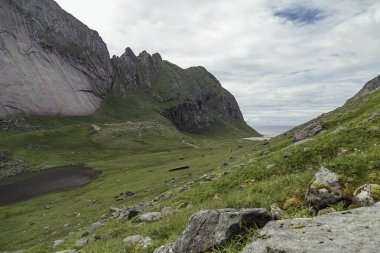 Lofoten Adaları 'ndaki Bunes Sahili' nin yemyeşil yeşillikleri çarpıcı kaya oluşumları ve engebeli dağları sergiliyor dramatik bir gökyüzü altında, yürüyüş maceraları için mükemmel..